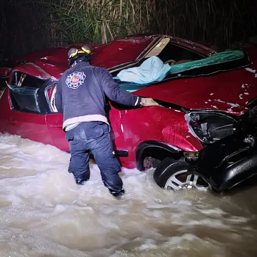 Los rescatistas se acercaron al carro que se accidentó para sacar a los ocho pasajeros, en medio de una fuerte corriente de agua.