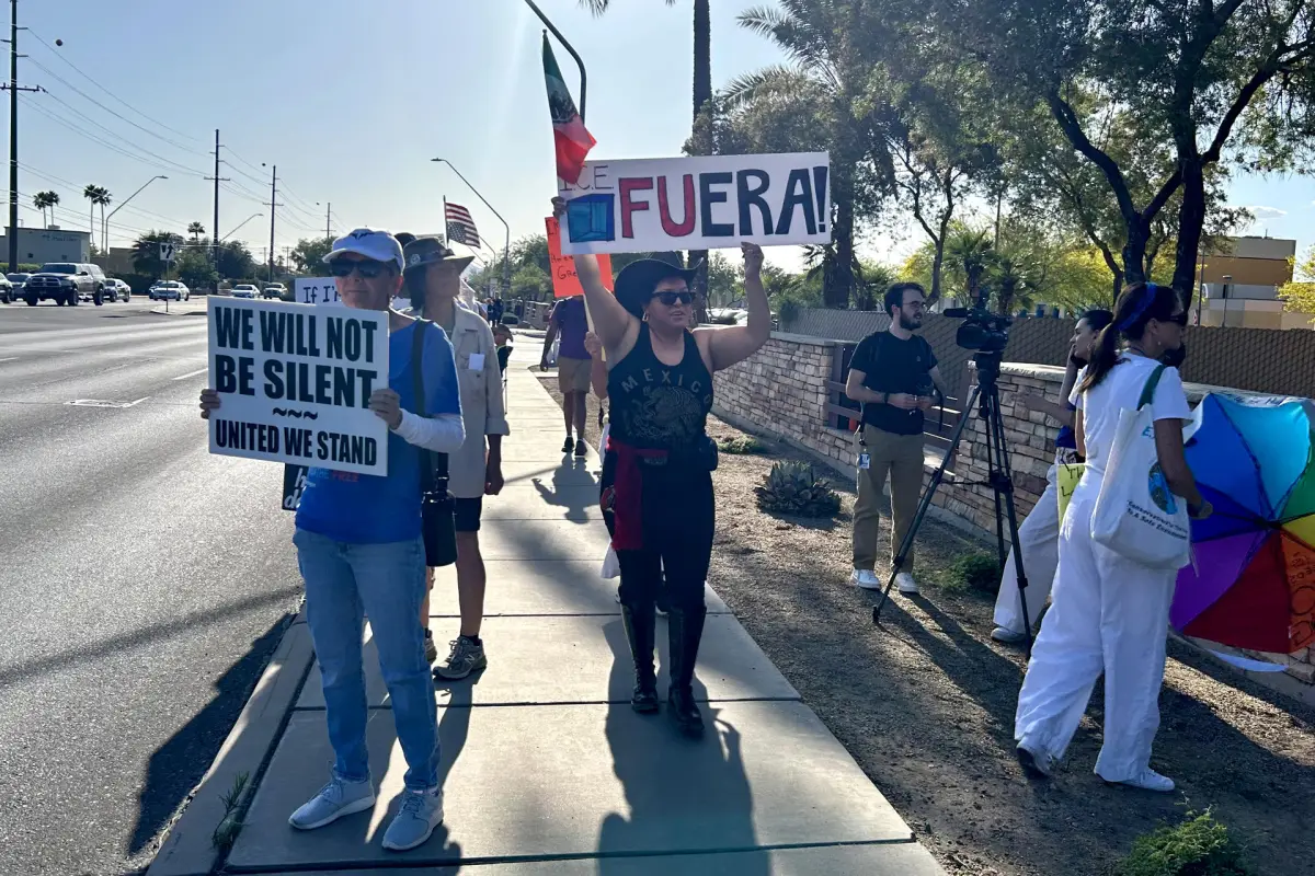 Personas sostienen carteles y banderas durante una manifestación este sábado, en Tucson (Estados Unidos),  EFE/ María León
