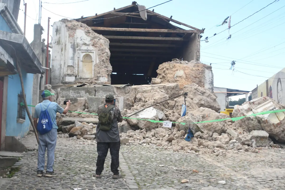 Personas observan este miércoles una edificación destruida por los temblores ocurridos el martes, en Santa María de Jesús., EFE