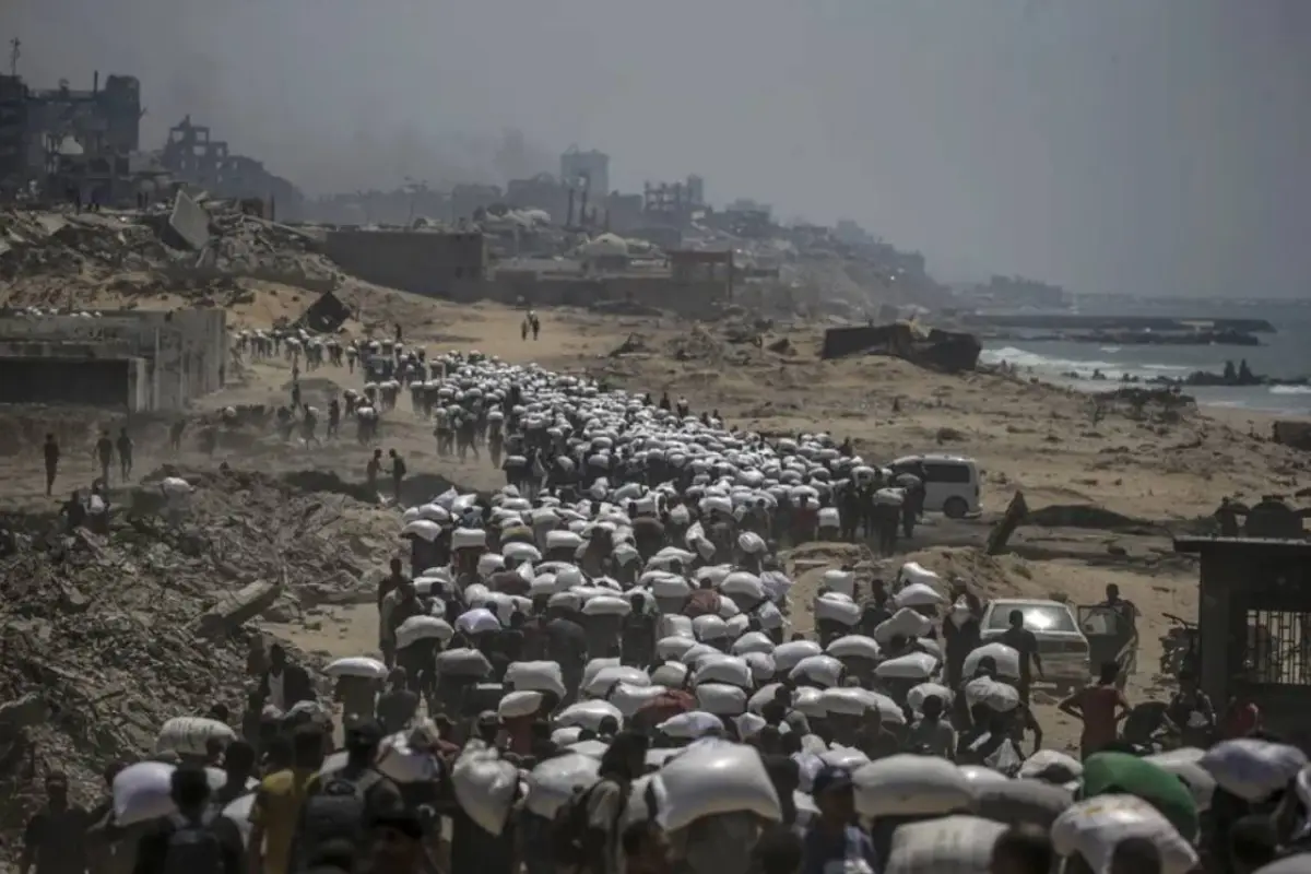 Palestinos desplazados llevan bolsas de harina cerca de un punto de distribución de alimentos, en Zikim, al norte de la Franja de Gaza. , EFE. 