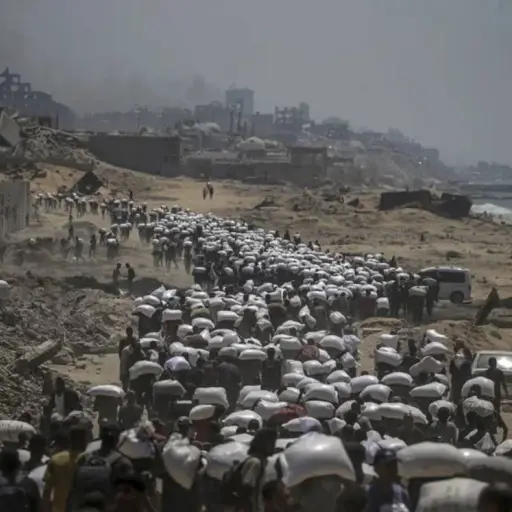 Palestinos desplazados llevan bolsas de harina cerca de un punto de distribución de alimentos, en Zikim, al norte de la Franja de Gaza.  ,EFE. 