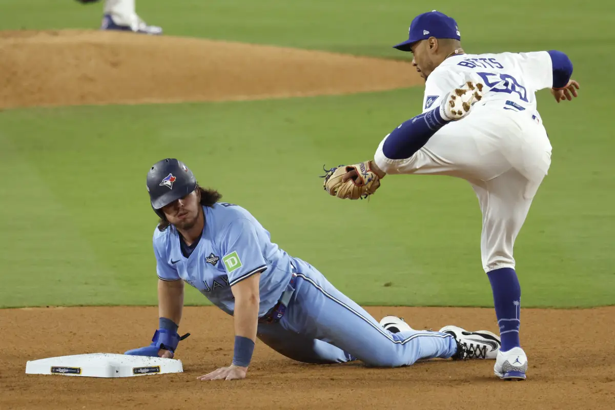 Addison Barger (izq.) de los Azulejos de Toronto se desliza de regreso a la segunda base en un intento de robo por parte del campocorto de los Dodgers de Los Ángeles Mookie Betts (der.) en el quinto juego de la Serie Mundial