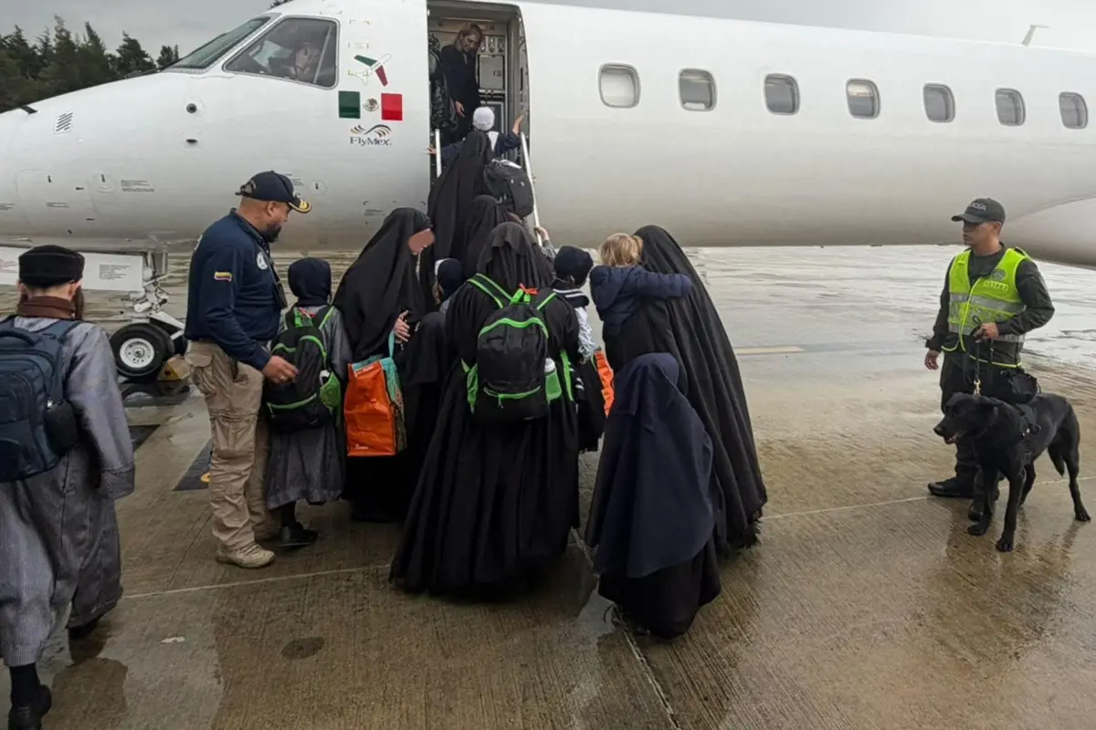 Imagen cedida por la oficina de comunicaciones de Migración Colombia que muestra a integrantes de Lev Tahor subiendo a un avión luego de ser expulsados del país hacia EE. UU., EFE