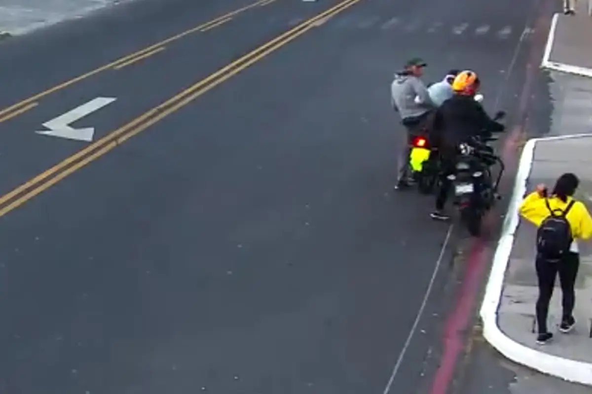 El motorista vestido de negro fue víctima de asalto por los otros dos hombres que están frente a él., Captura de pantalla. 