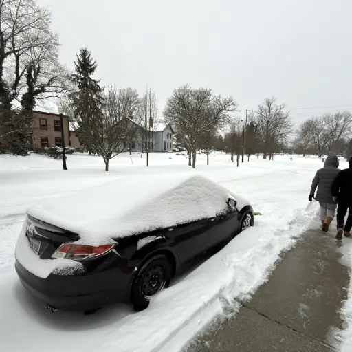 Dos personas caminan al lado de una calle afectada por la nieve este domingo en la ciudad de Hudson, Ohio (EE ,UU