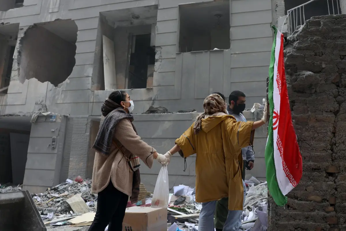 Dos hermanas iraníes se dan la mano frente a un edificio dañado en el sur de Teherán, Irán, el 15 de marzo de 2026, EFE/EPA/ABEDIN TAHERKENAREH