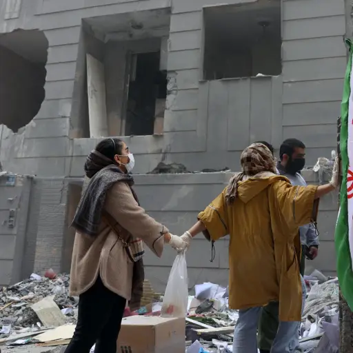 Dos hermanas iraníes se dan la mano frente a un edificio dañado en el sur de Teherán, Irán, el 15 de marzo de 2026 , EFE/EPA/ABEDIN TAHERKENAREH