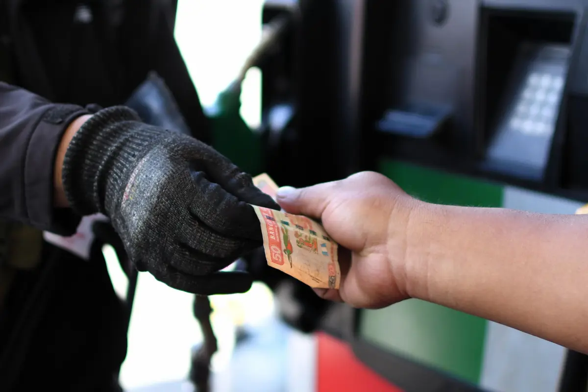 Una persona entrega dinero en una estación de gasolina en Ciudad de Guatemala, EFE