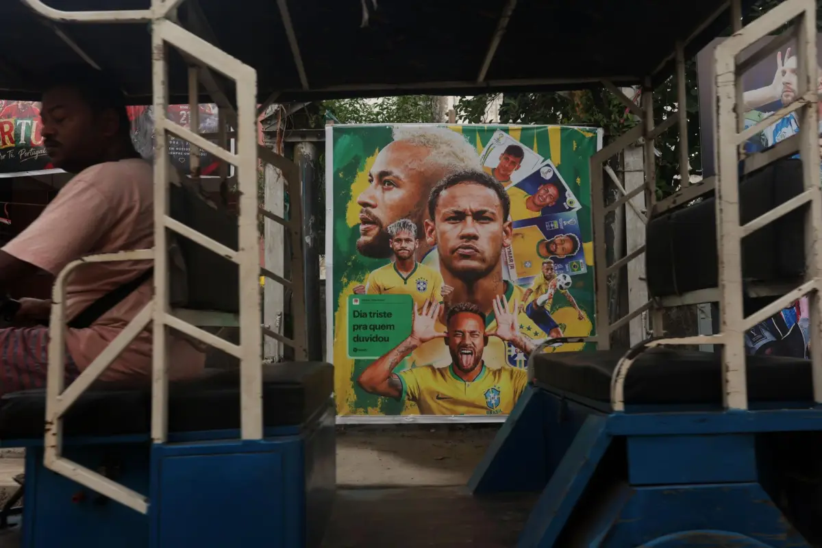 Un rickshaw pasa junto a un mural con imágenes de futbolistas brasileños en Howrah, Calcuta, en India., EFE