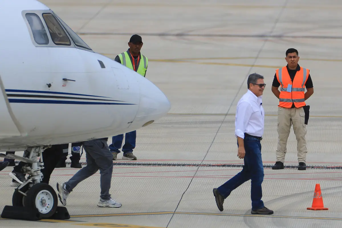 El expresidente hondureño Juan Orlando Hernández (c) (2014-2022) caminando este domingo, a su llegada al Aeropuerto Internacional de Palmerola en Comayagua (Honduras),  EFE/ Gustavo Amador
