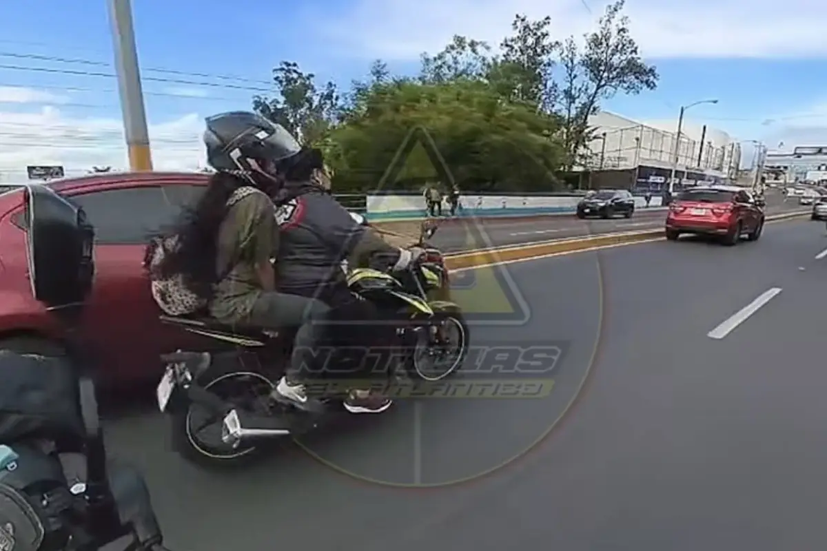 Motociclistas rebasan vehículos, pierden el control y terminan debajo de un picop., Captura de pantalla video de Facebook.