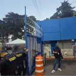 Agentes de la PNC resguardan el portón del ingreso a la USAC durante los allanamientos. ,Ministerio Público.