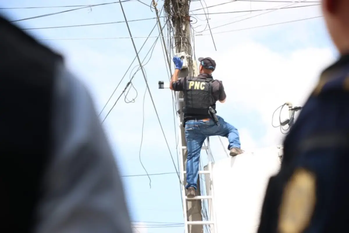 Varios agentes suben a lo alto de los postes para retirar las cámaras instaladas sin autorización., PNC de Guatemala.