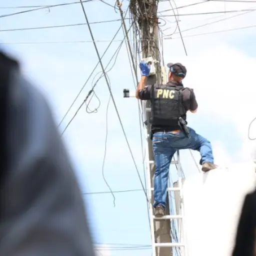 Varios agentes suben a lo alto de los postes para retirar las cámaras instaladas sin autorización. ,PNC de Guatemala.